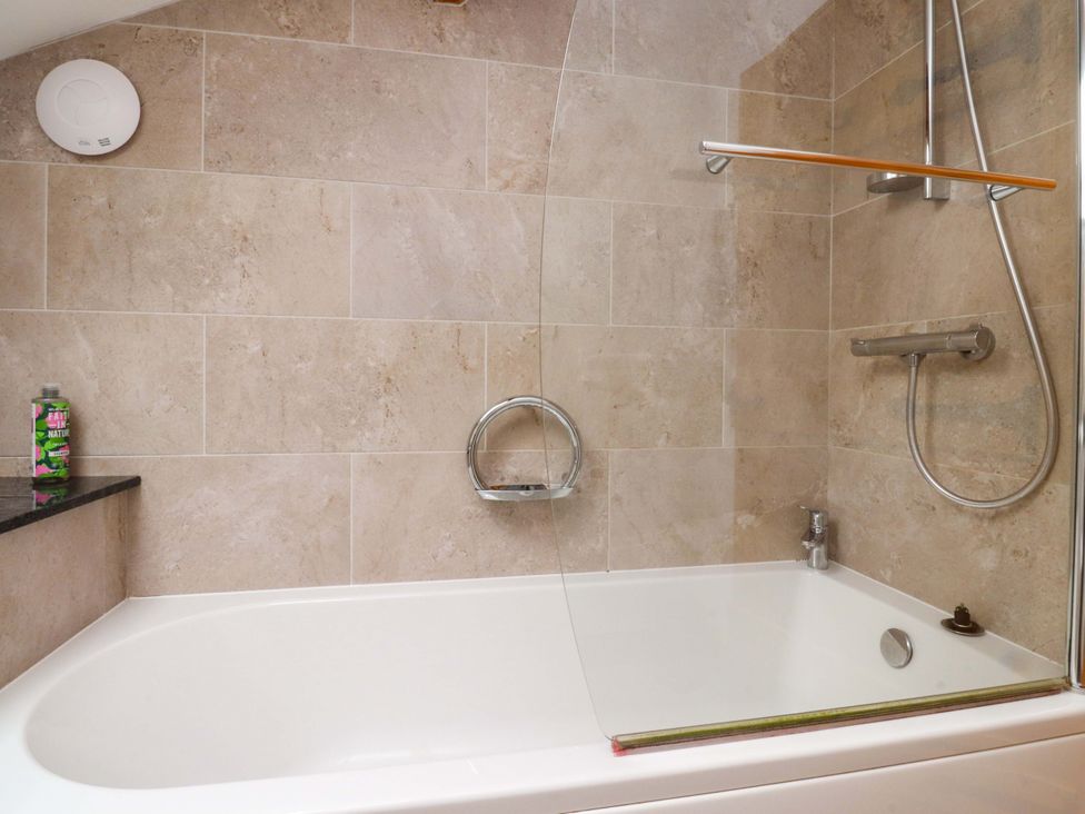 A bathroom with a bathtub and shower features at Rowan Tree Cottage in Skipsea