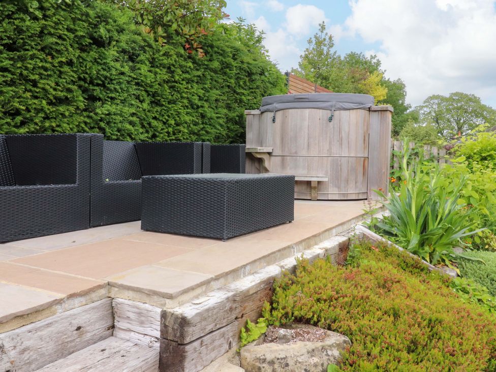 A garden with seating area and wooden hot tub at Rowan Tree Cottage in Skipsea