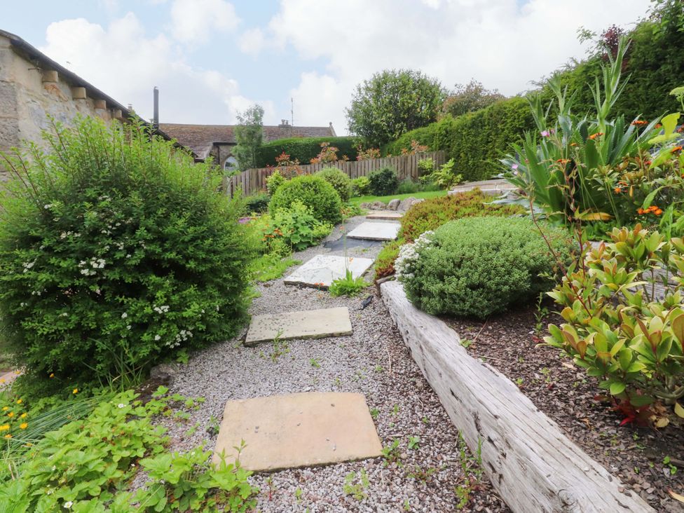 A garden with a pathway and greenery at Rowan Tree Cottage in Skipsea