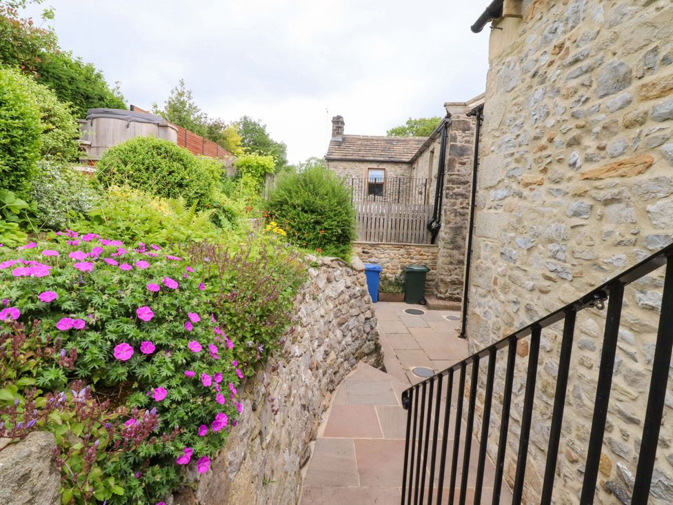 A pathway with flowers and a stone wall at Rowan Tree Cottage in Skipsea