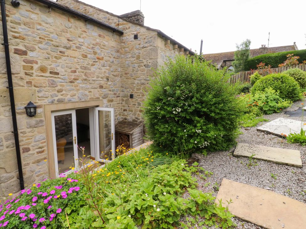 A garden with flowers and a stone wall at Rowan Tree Cottage in Skipsea