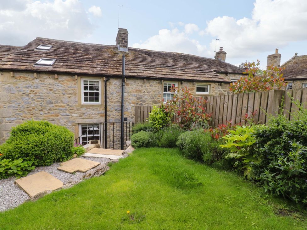 A garden with grass and stones at Rowan Tree Cottage in Skipsea