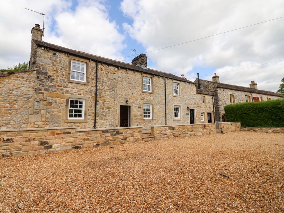 An outdoor view of a stone house with gravel and greenery at Rowan Tree Cottage Skipsea