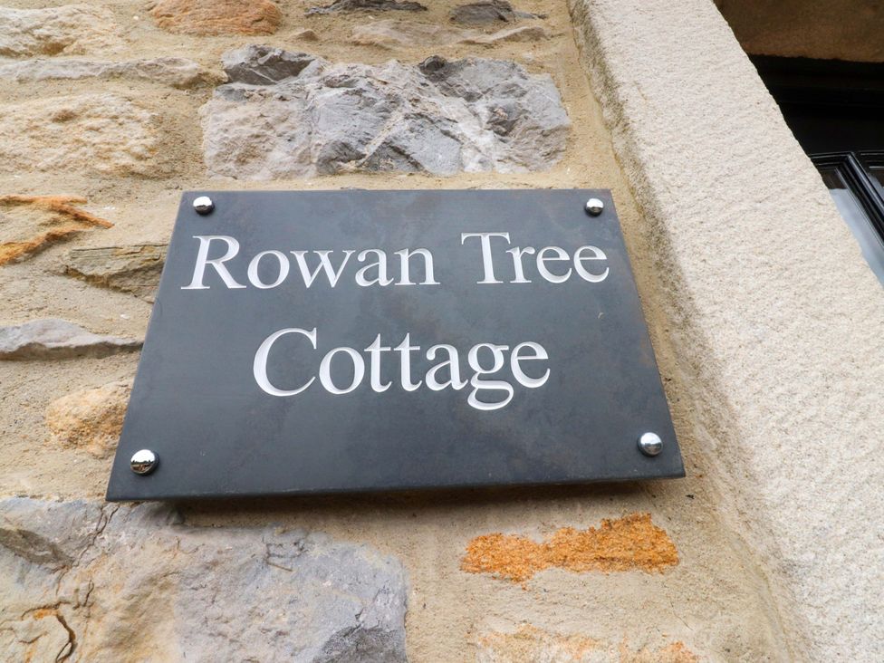 A sign that says Rowan Tree Cottage on a stone wall at Rowan Tree Cottage Skipsea