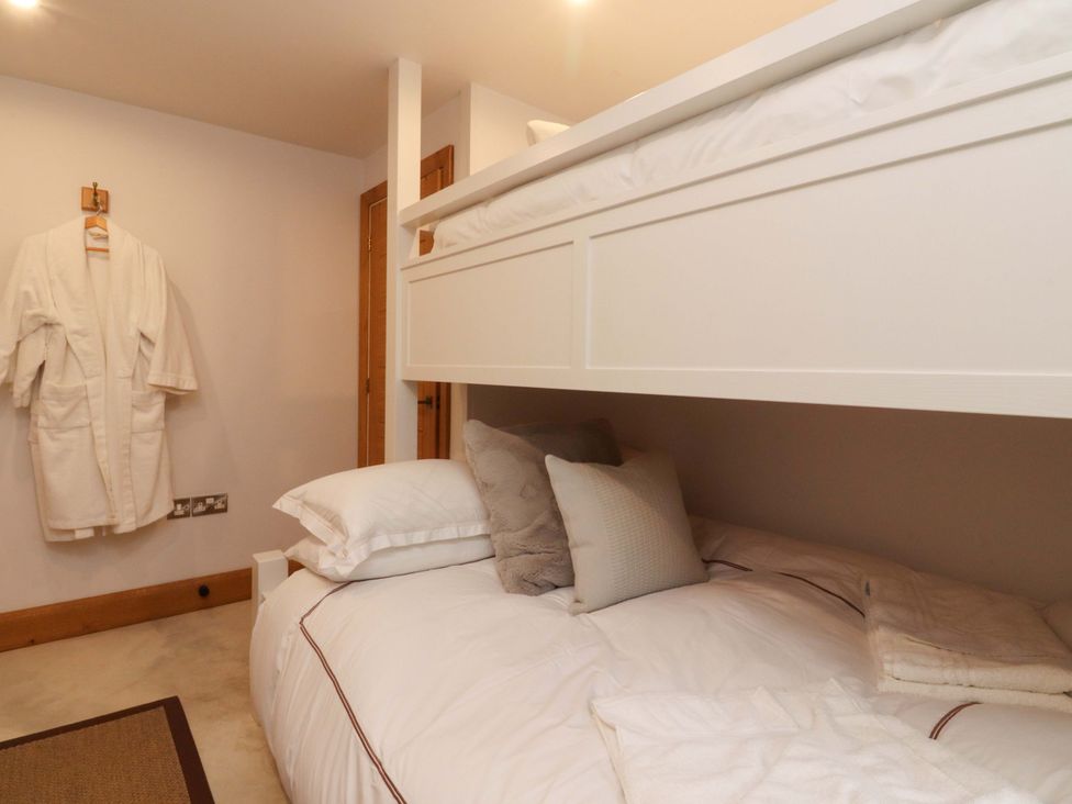 A bunk bed with white bedding and a robe hanging at Welly Bob Cottage in Airton
