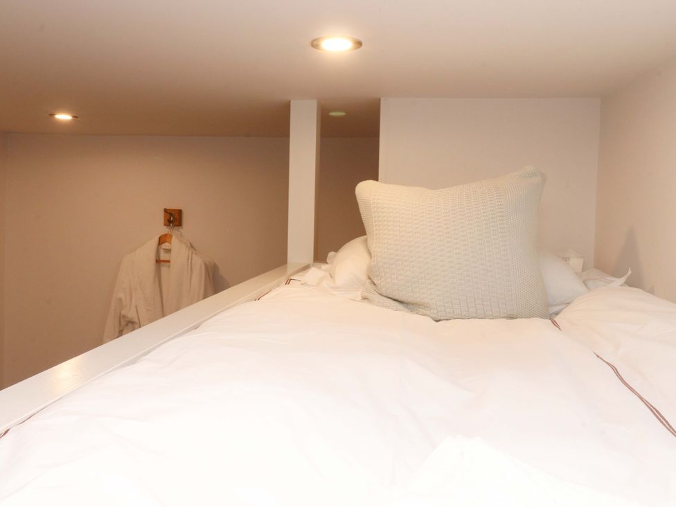 A loft bed with a pillow and blanket at Welly Bob Cottage in Airton