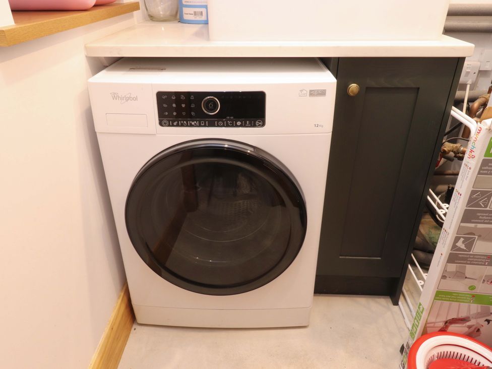 A washing machine next to a cabinet in a laundry room at Welly Bob Cottage in Airton