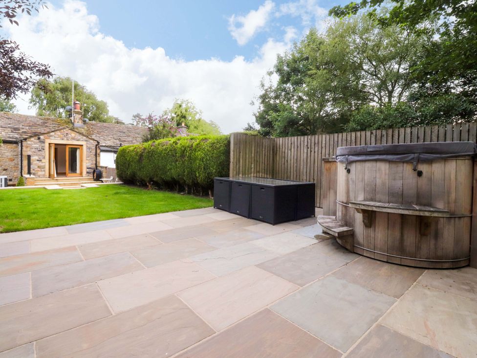 A garden with a hot tub and storage box at Welly Bob Cottage Airton