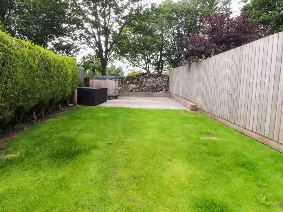A garden with grass and a patio at Welly Bob Cottage in Airton