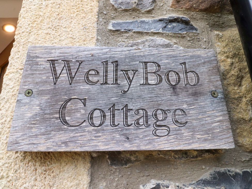 A wooden sign with WellyBob Cottage engraved on it