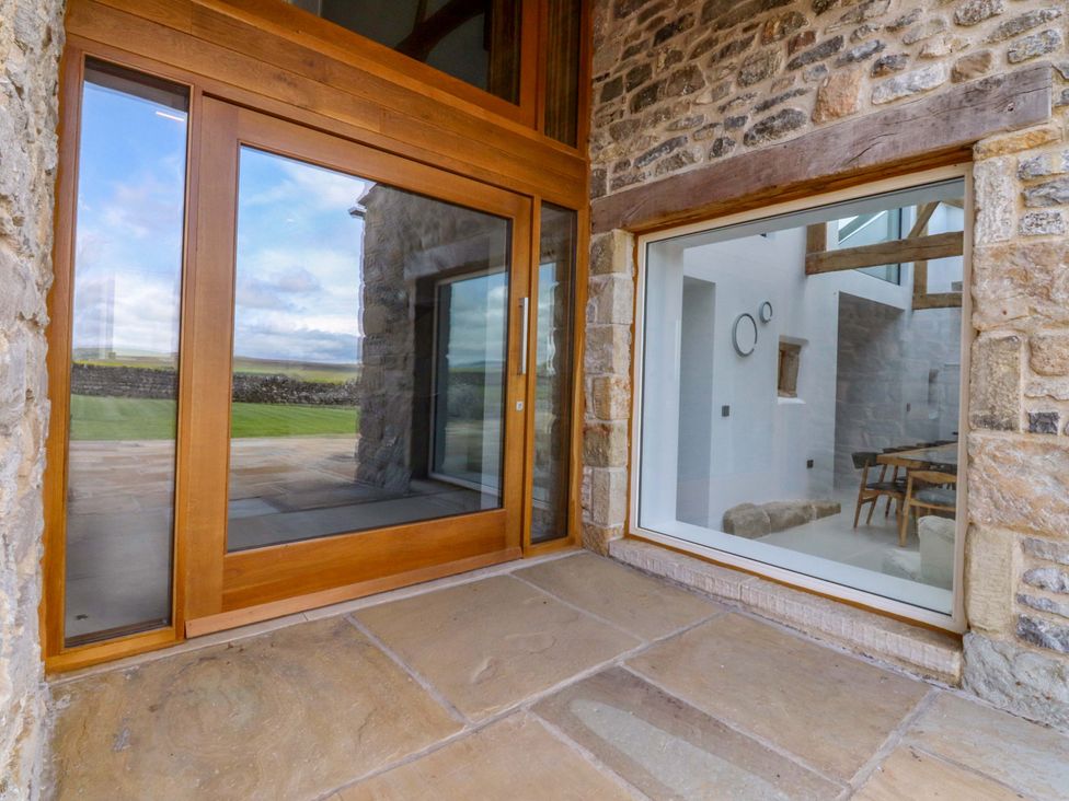 A view of an entrance with glass doors and stone wall at Carden Laithe Barn Threshfield
