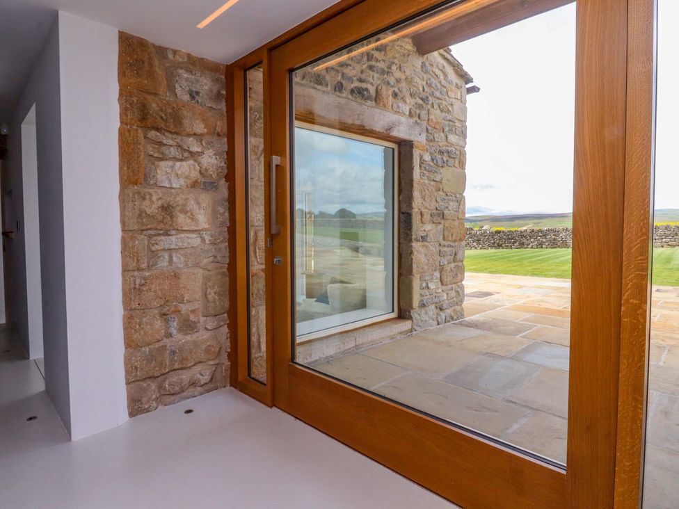 A glass door and stone wall leading to a patio at Carden Laithe Barn in Threshfield