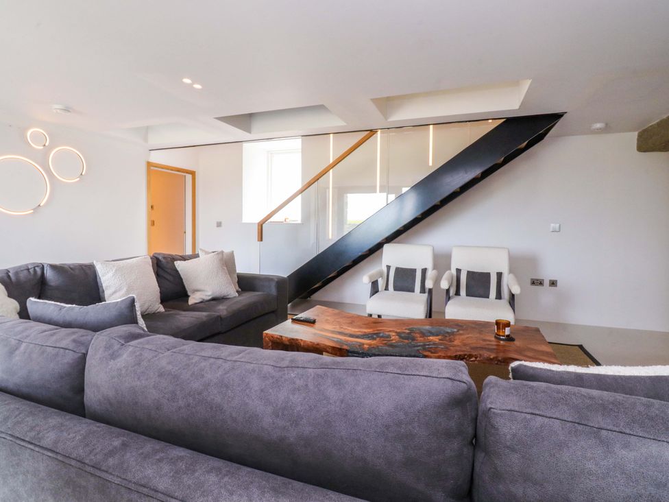 A living room with a sofa, chairs and a staircase at Carden Laithe Barn in Threshfield
