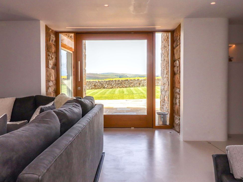 A living room with a sofa and glass door at Carden Laithe Barn in Threshfield