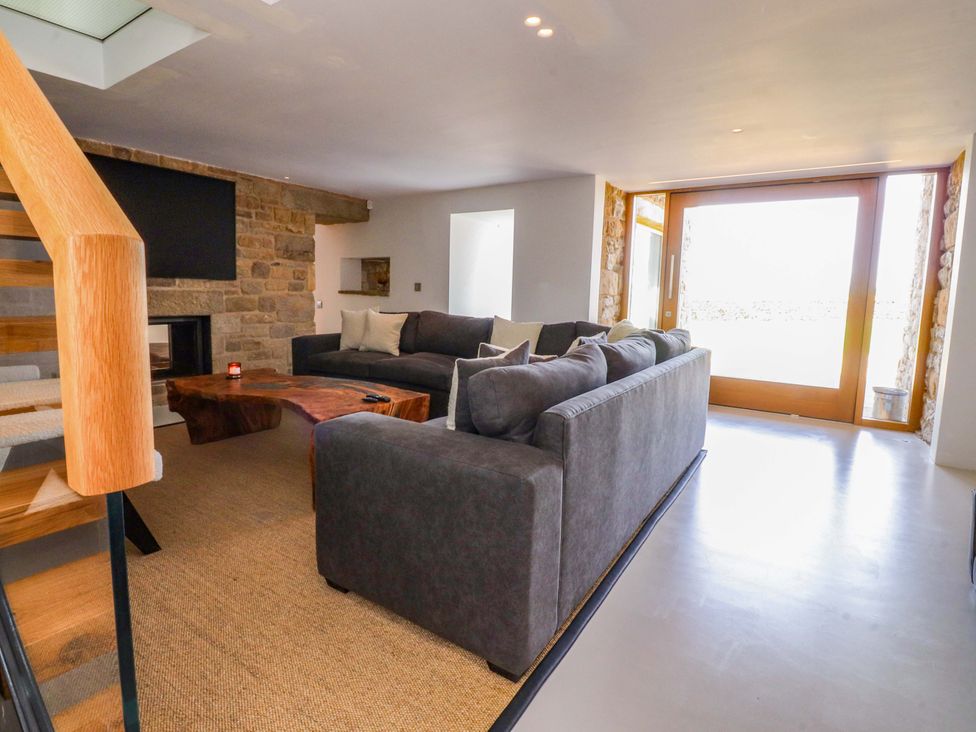 A living room with a fireplace and large windows at Carden Laithe Barn Threshfield
