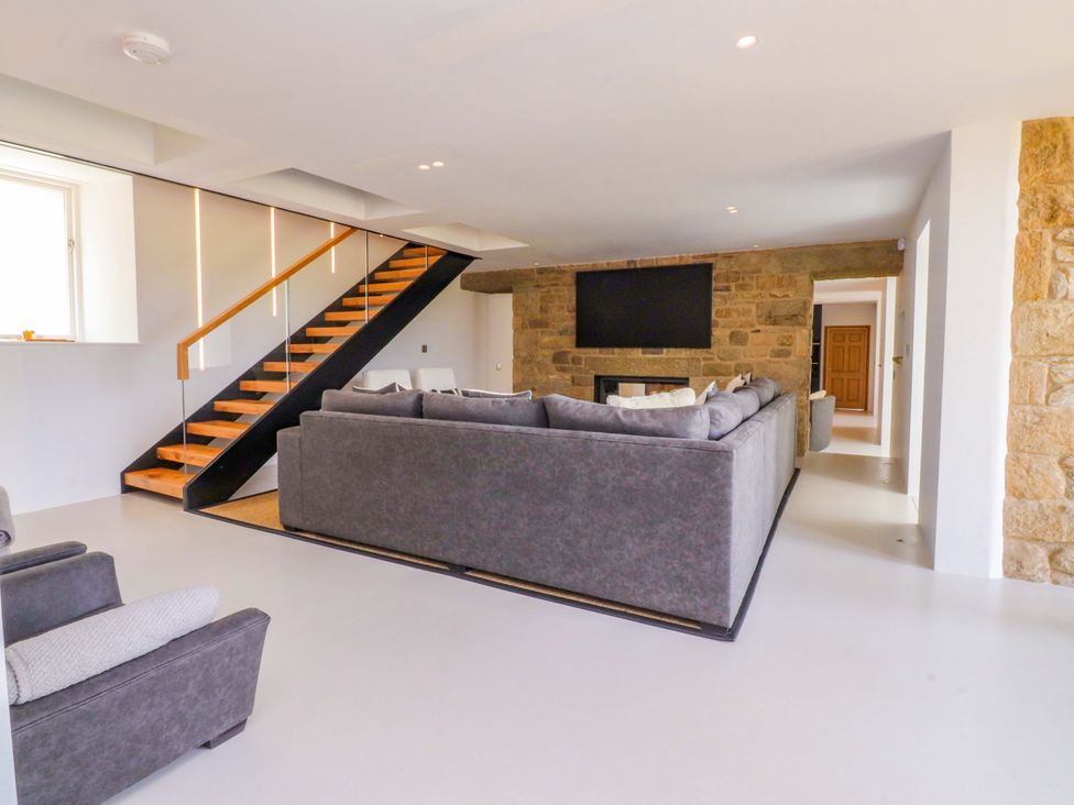 A living room with a sofa and staircase at Carden Laithe Barn in Threshfield