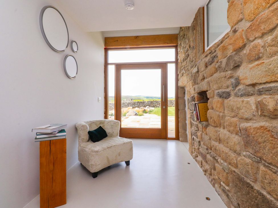 An entrance hall with a chair and books on a table at Carden Laithe Barn Threshfield
