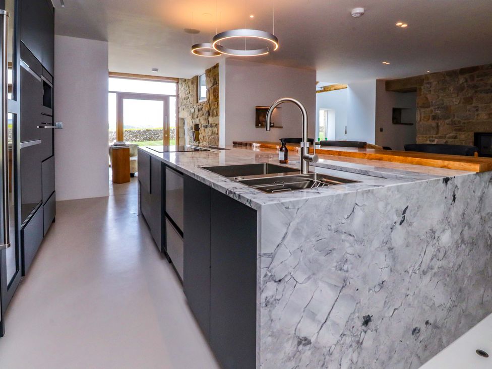A kitchen with a marble countertop and windows at Carden Laithe Barn Threshfield