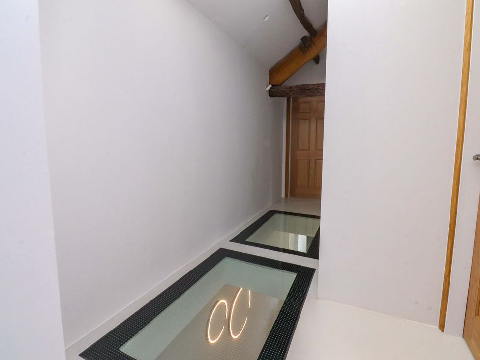 A hallway with glass flooring and wooden beams at Carden Laithe Barn in Threshfield