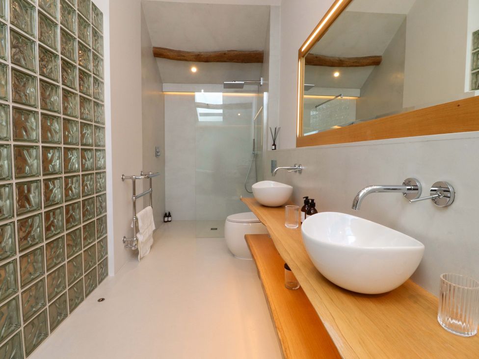 A bathroom with a glass block wall and washbasins at Carden Laithe Barn Threshfield
