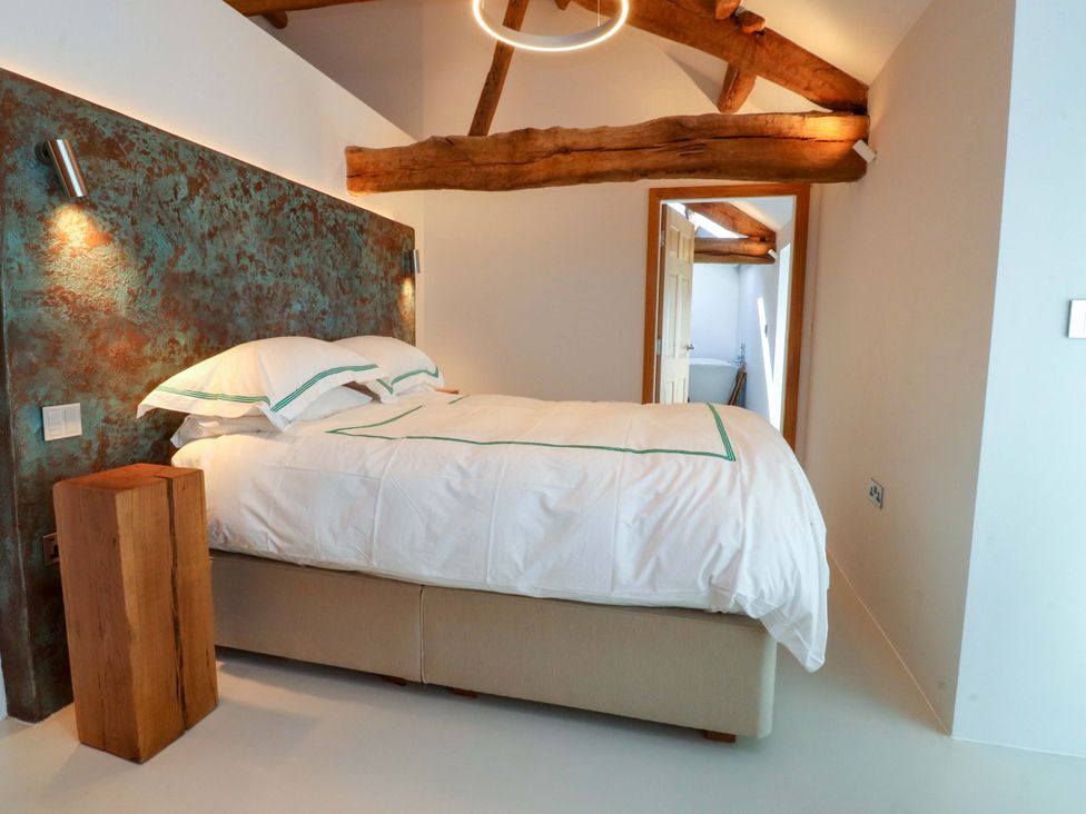 A bedroom with a bed and wooden beam at Carden Laithe Barn Threshfield