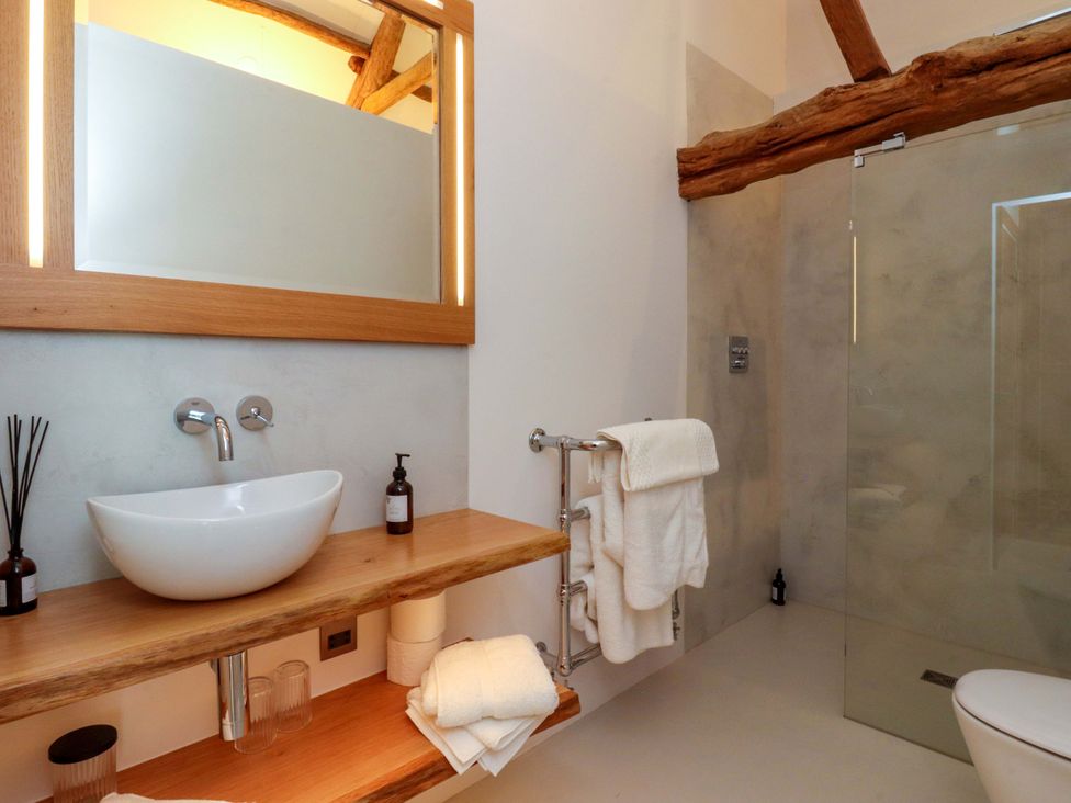 A bathroom with a sink, shower, and towels at Carden Laithe Barn in Threshfield