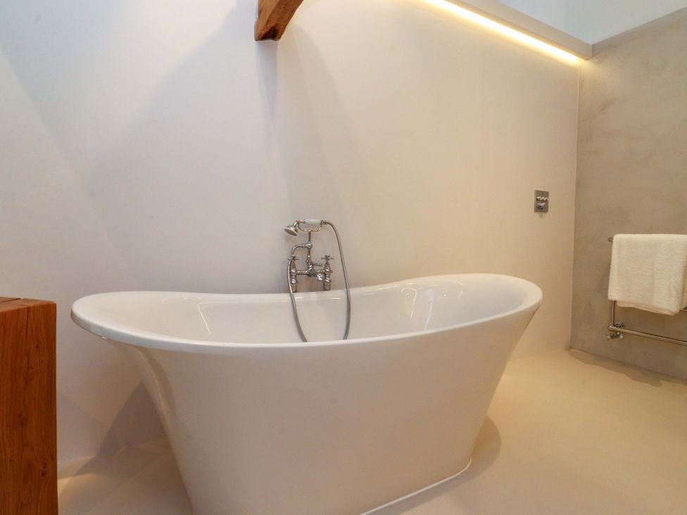 A bathroom with a bathtub and wooden stool at Carden Laithe Barn Threshfield