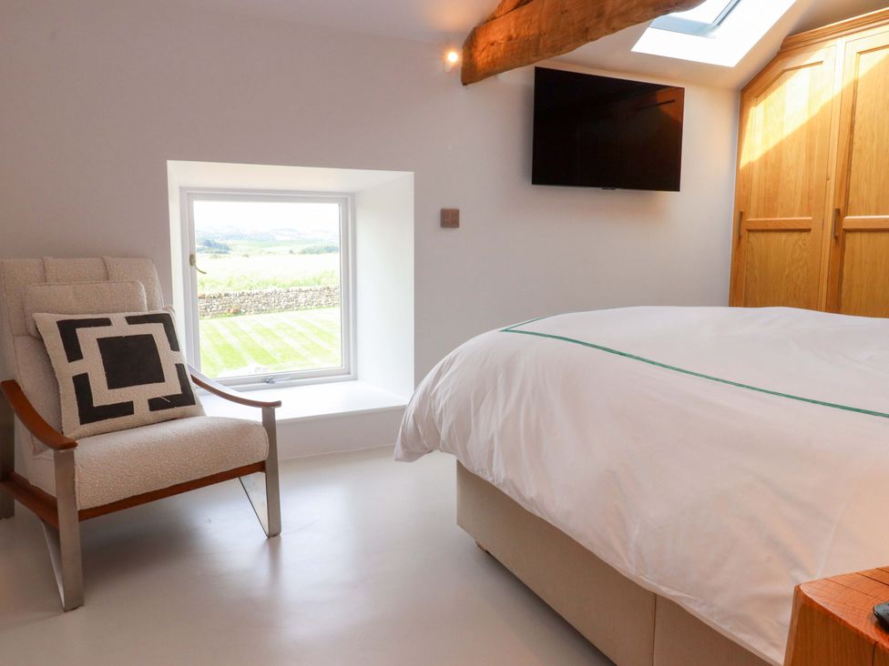 A bedroom with a bed and armchair at Carden Laithe Barn Threshfield