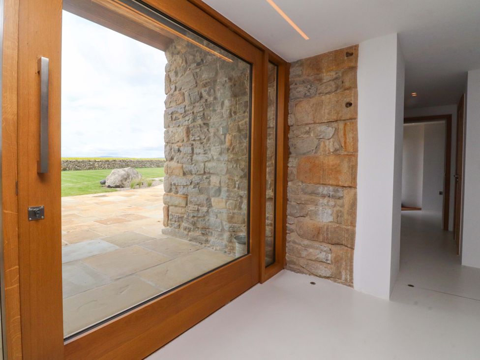 An entrance hall with a stone wall and a view of a garden at Carden Laithe Barn Threshfield