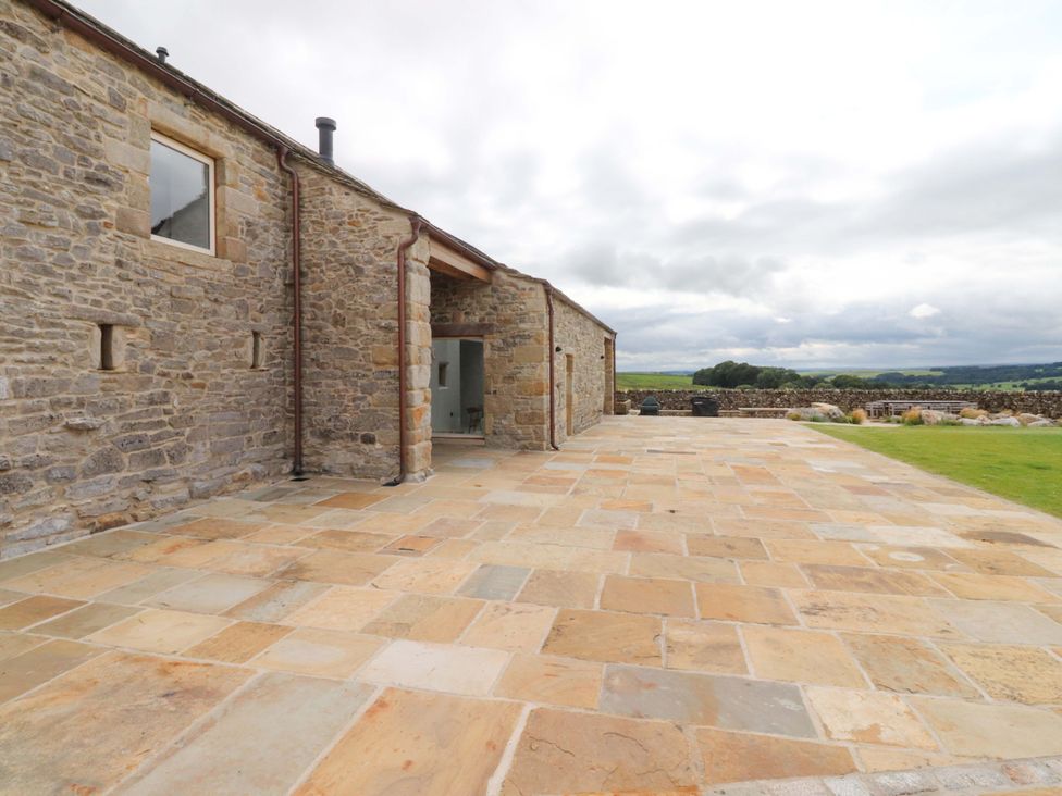 An outdoor area with a stone wall and paved patio at Carden Laithe Barn Threshfield