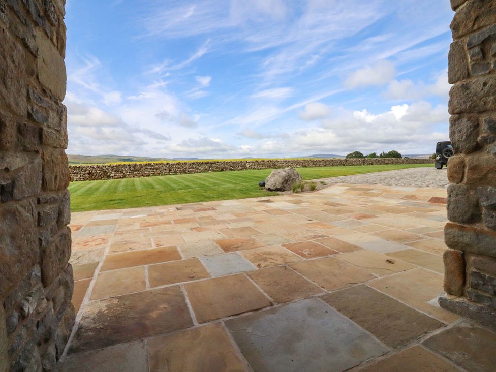 An outdoor area with a paved floor and grass at Carden Laithe Barn in Threshfield