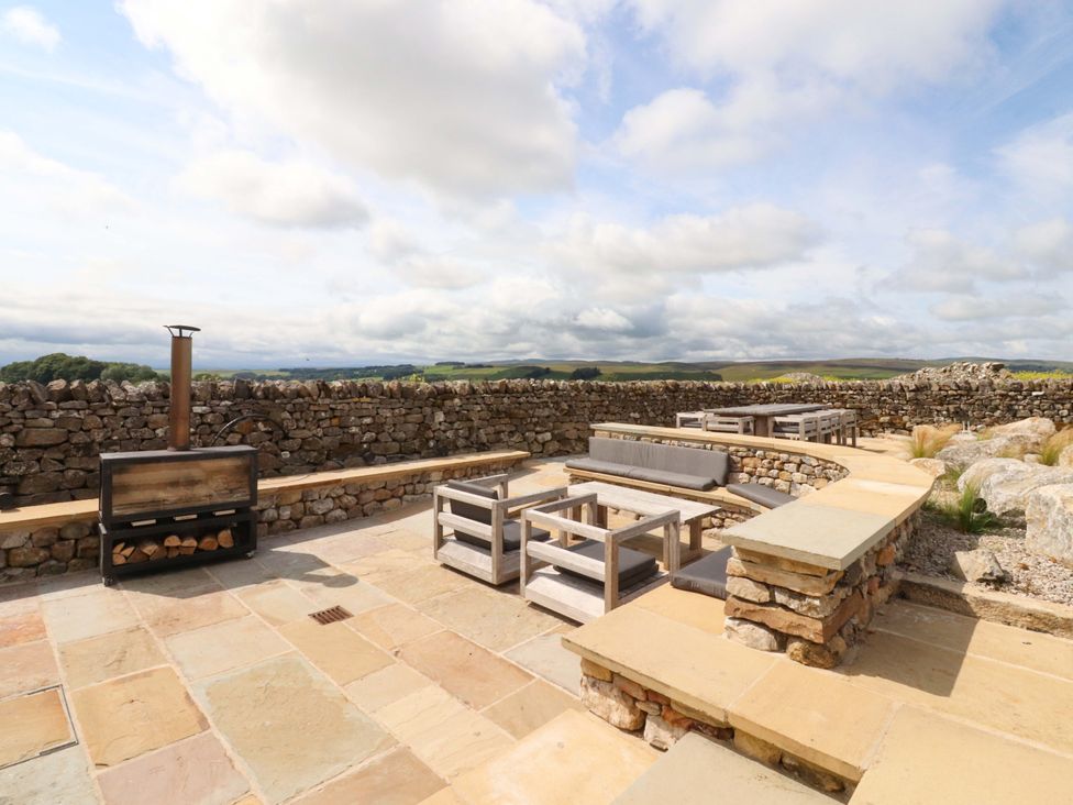 An outdoor seating area with a fireplace and stone wall at Carden Laithe Barn Threshfield