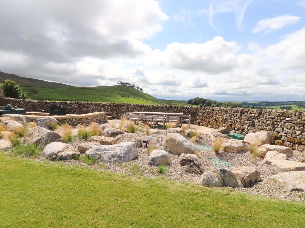 A garden with rocks and a wooden table at Carden Laithe Barn Threshfield