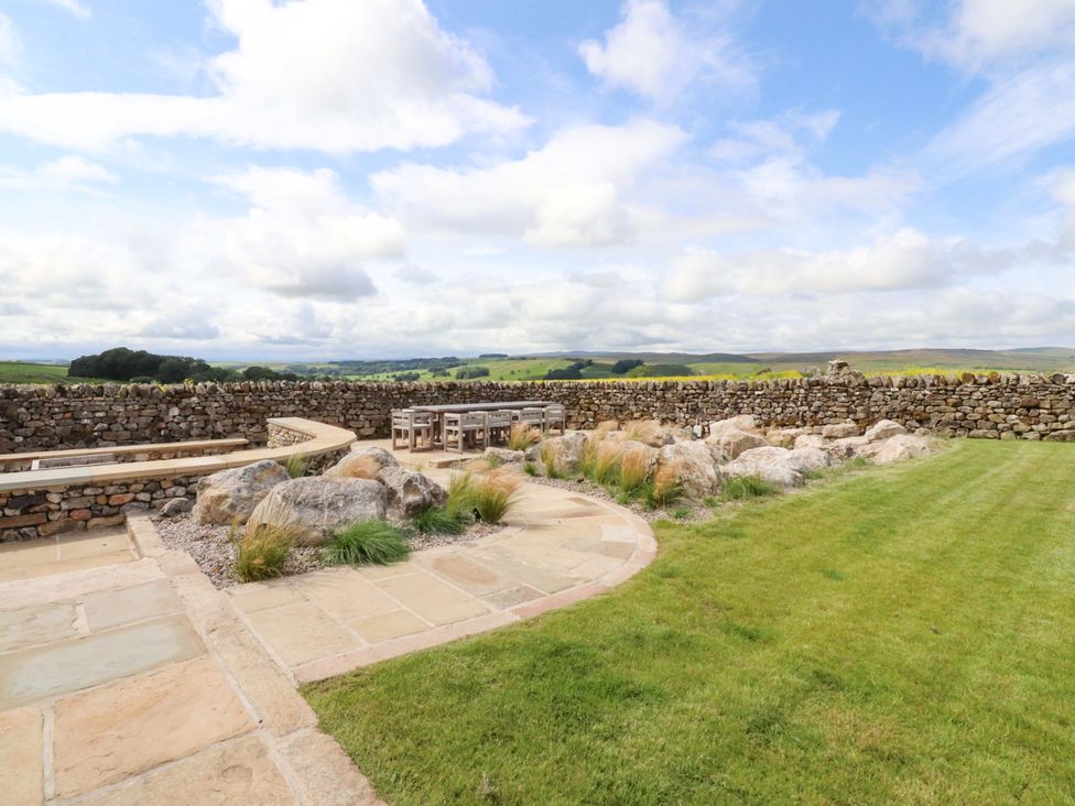 A garden with a stone wall and seating area at Carden Laithe Barn Threshfield