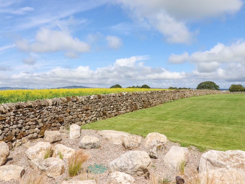 An outdoor area with a stone wall and grass near Carden Laithe Barn in Threshfield