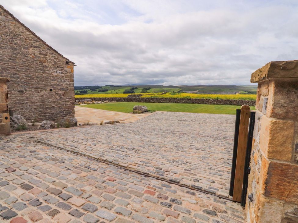 A cobblestone driveway with a stone building and grassy area at Carden Laithe Barn Threshfield