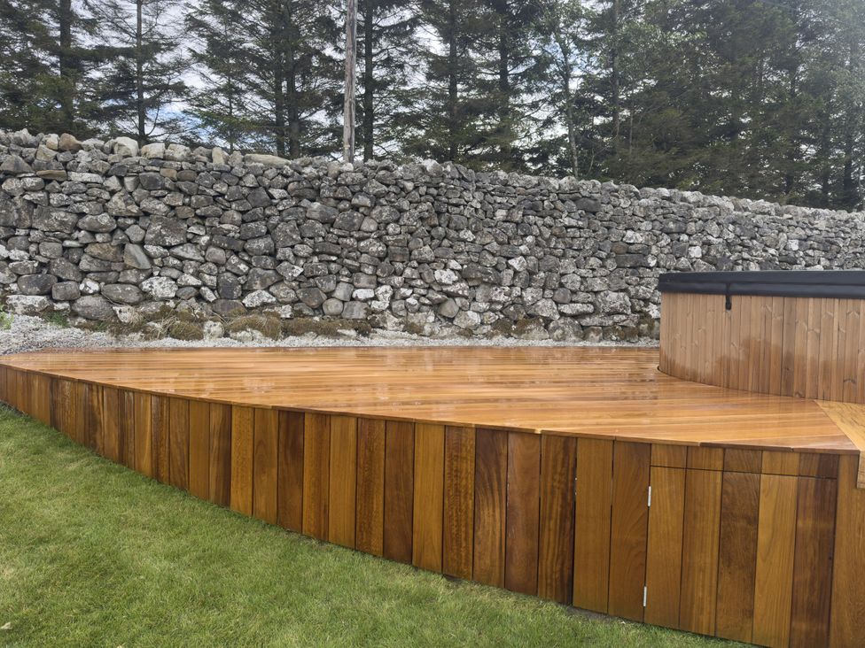An outdoor space with a wooden deck and hot tub at Carden Laithe Barn Cracoe