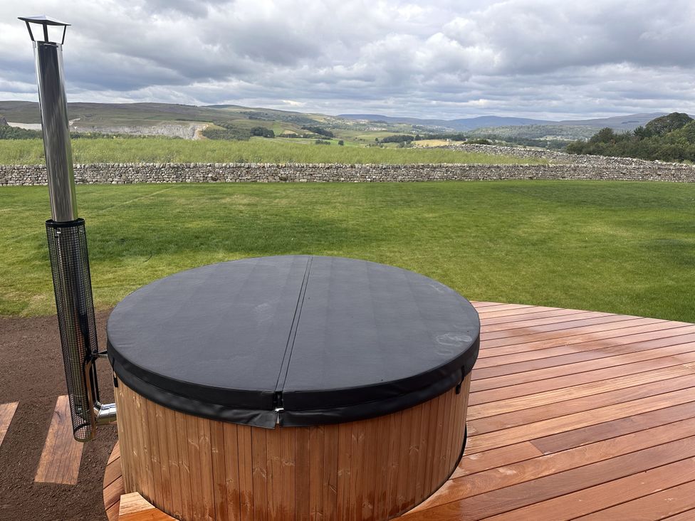 An outdoor area with a hot tub on a wooden deck at Carden Laithe Barn in Cracoe