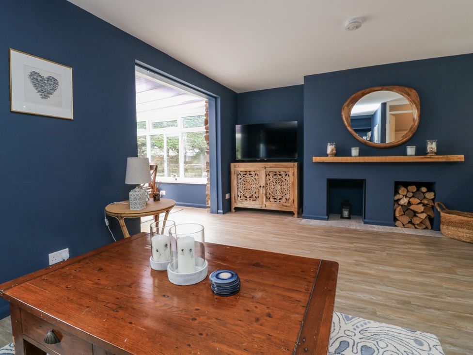 A living room with a wooden table and television at 1 Island View Thurlestone