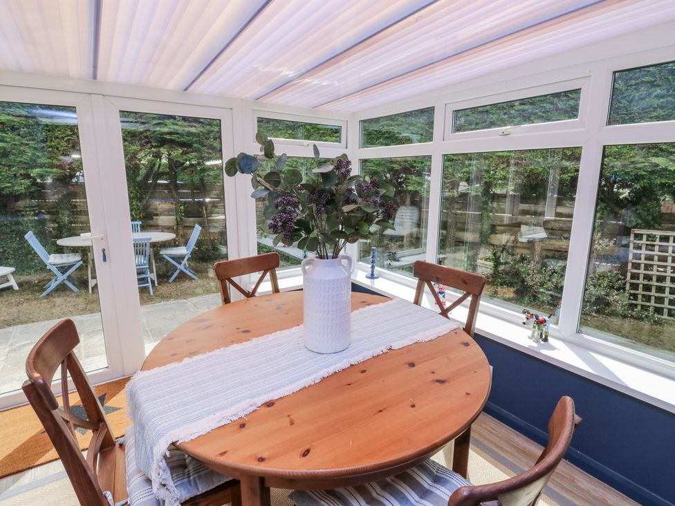 A table with chairs and a vase in a conservatory at 1 Island View Thurlestone