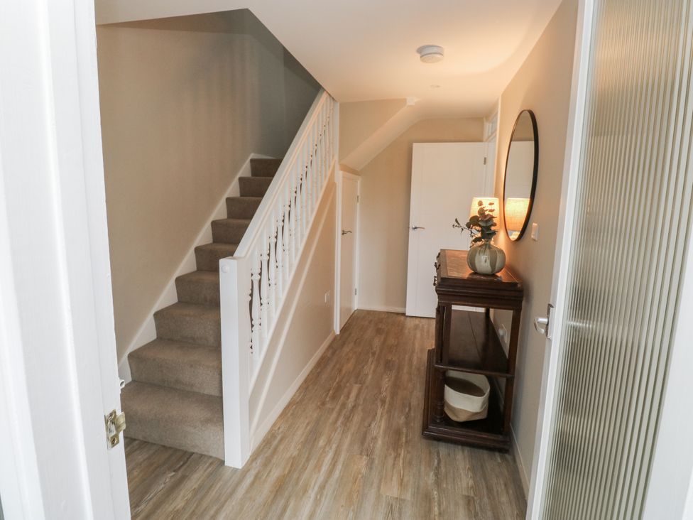 A hallway with a staircase and console table at 1 Island View in Thurlestone