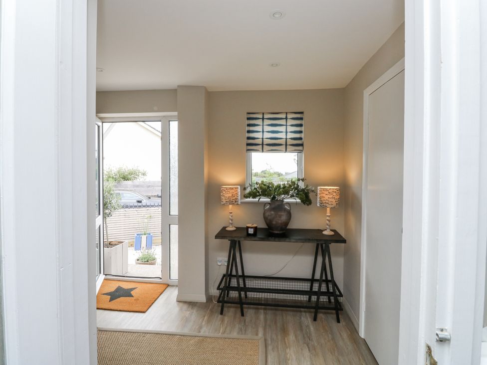 A hallway with a table, lamps, and a window at 1 Island View in Thurlestone