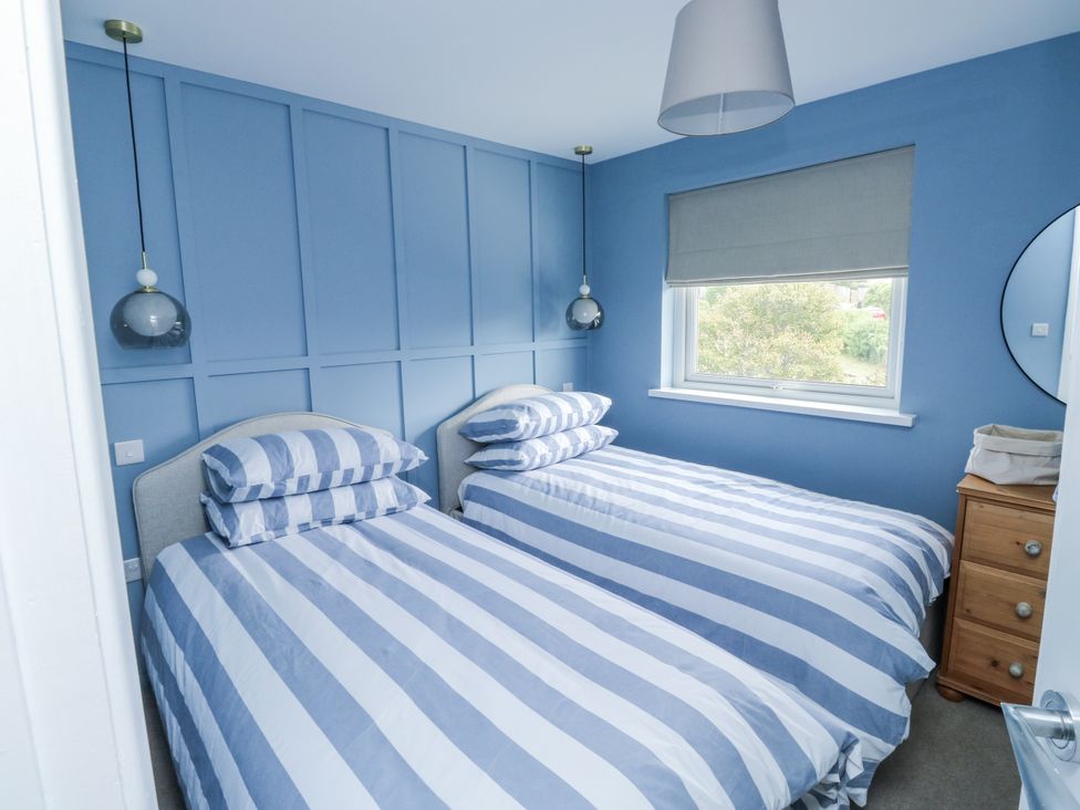A bedroom with two striped beds at 1 Island View in Thurlestone