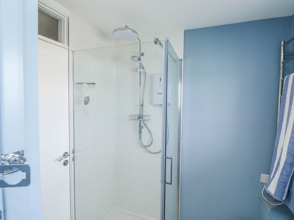 A shower with glass enclosure and towel rack at 1 Island View in Thurlestone