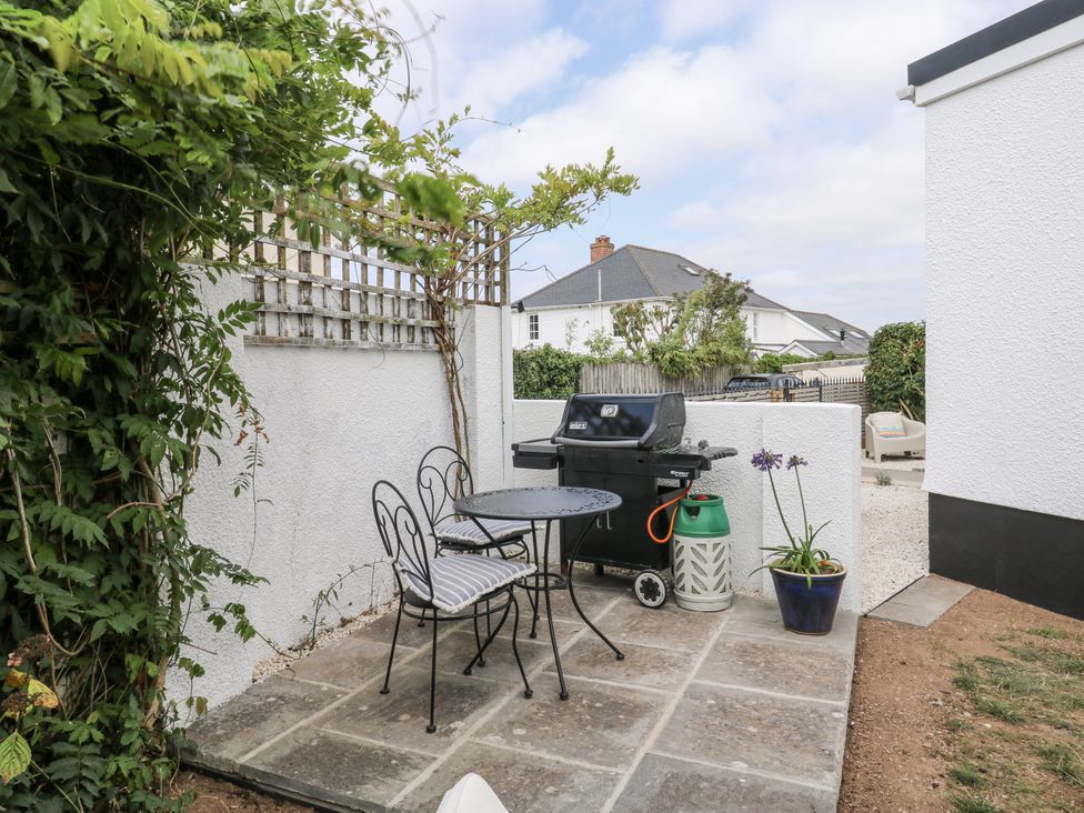 An outdoor dining area with a table and chairs beside a barbecue grill at 1 Island View Thurlestone