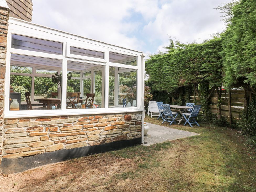 A conservatory with a dining table and garden at 1 Island View Thurlestone