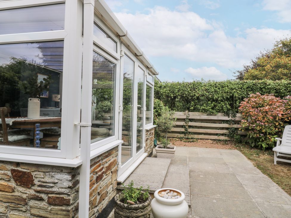 A conservatory with a table and chairs overlooking the garden at 1 Island View Thurlestone