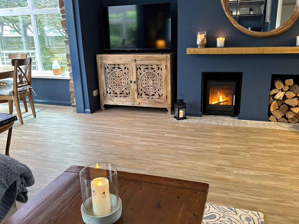 A living room with a television, wooden cabinet, and a fireplace at Thurlestone, 1 Island View in Thurlestone