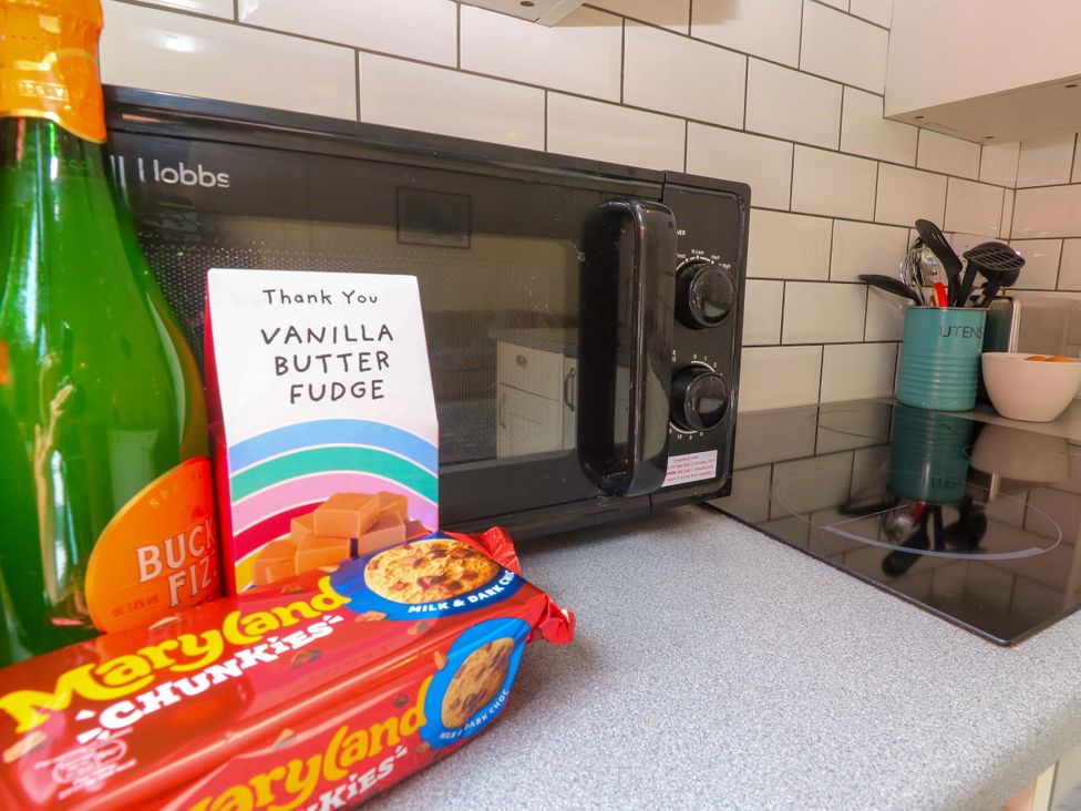 A kitchen with a microwave, bottle, fudge, and cookies at The Cow Shed