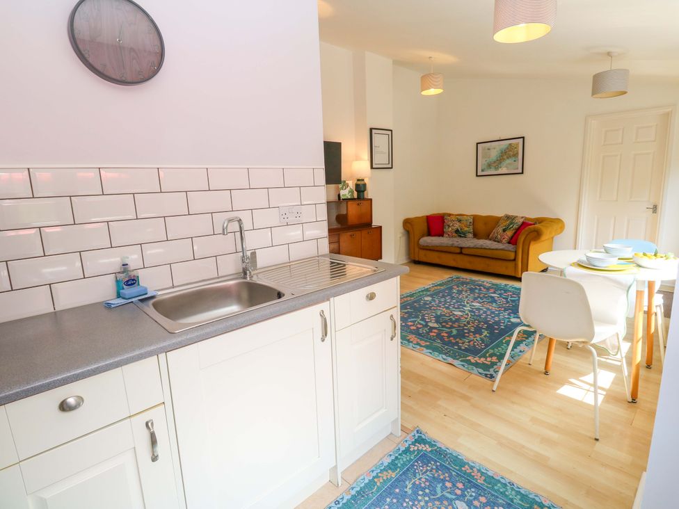 A kitchen with a sink and a sofa in the background at The Cow Shed